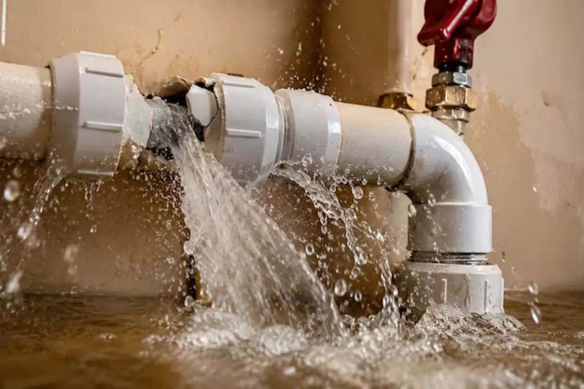 Water spraying from a burst pipe joint along a wall