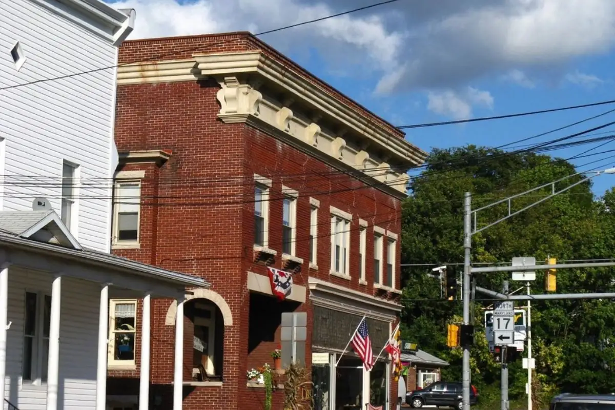 Brick storefront building at a small-town intersection with an American flag