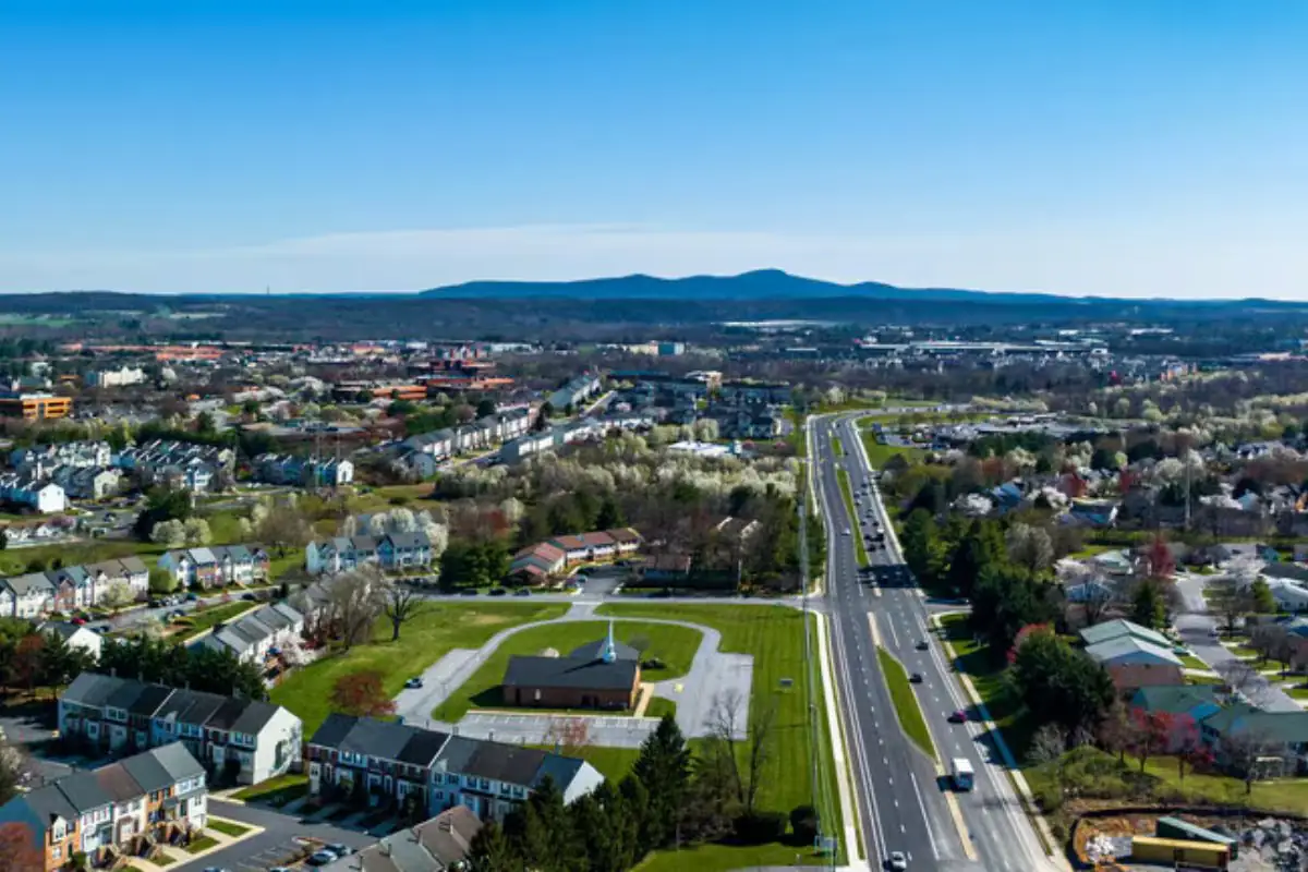 Aerial view of a suburban road, townhomes and a green park with mountains in the distance