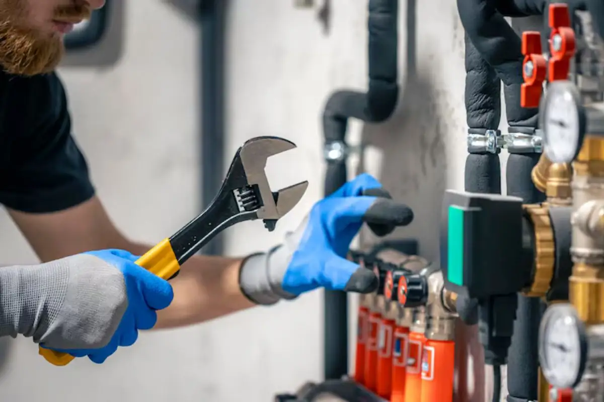 Gloved hand tightening fittings on a PEX manifold with color-coded lines