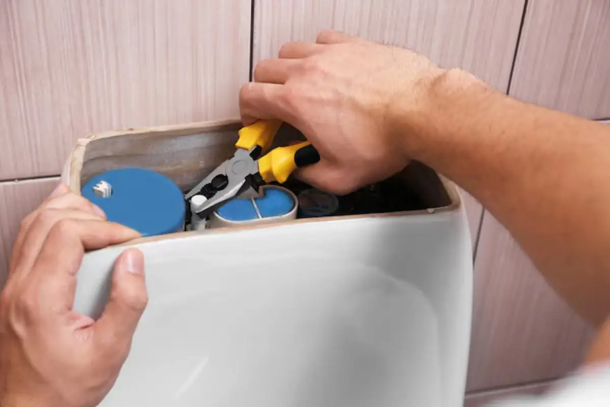 Hands adjusting the fill valve inside an open toilet tank