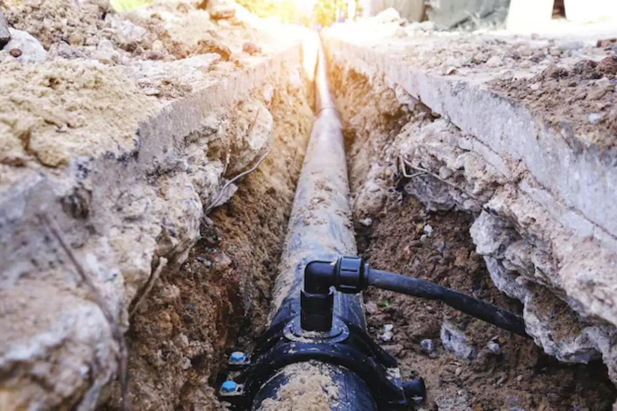 Open trench with a buried water service line and black fittings